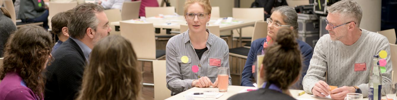 Gruppe von Menschen sitzen am Tisch und diskutieren